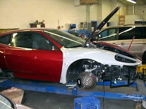 Step 5: Side view of the red Ferrari on the frame bench with a new white primed front fender and the front wheel removed