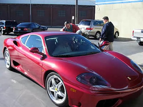 After: the same Ferrari fully repaired and repainted, parked outside the shop